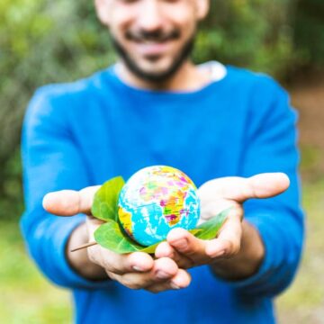 Activista sosteniendo un globo y una hoja verde sonriendo.